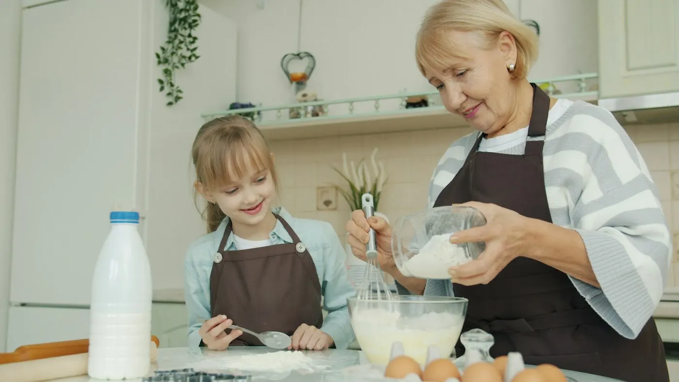 A grandmother and granddaughter baking together in a bright kitchen