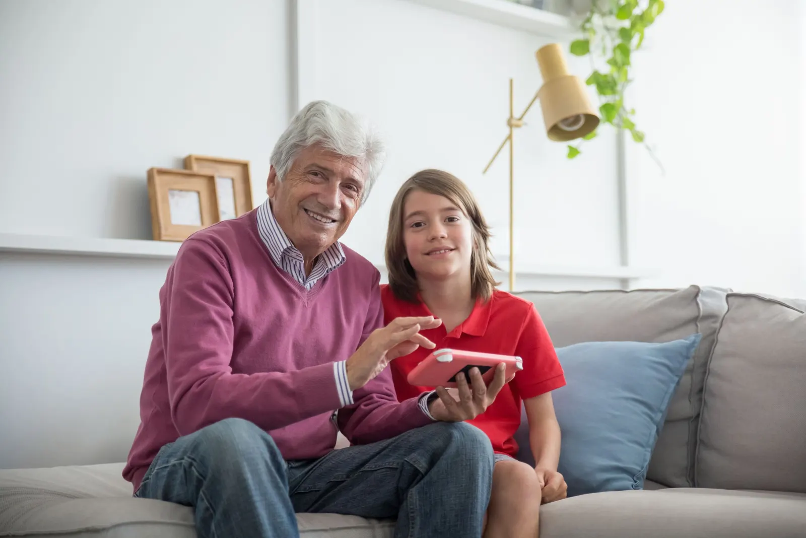 An older man and a younger relative smiling together on a sofa