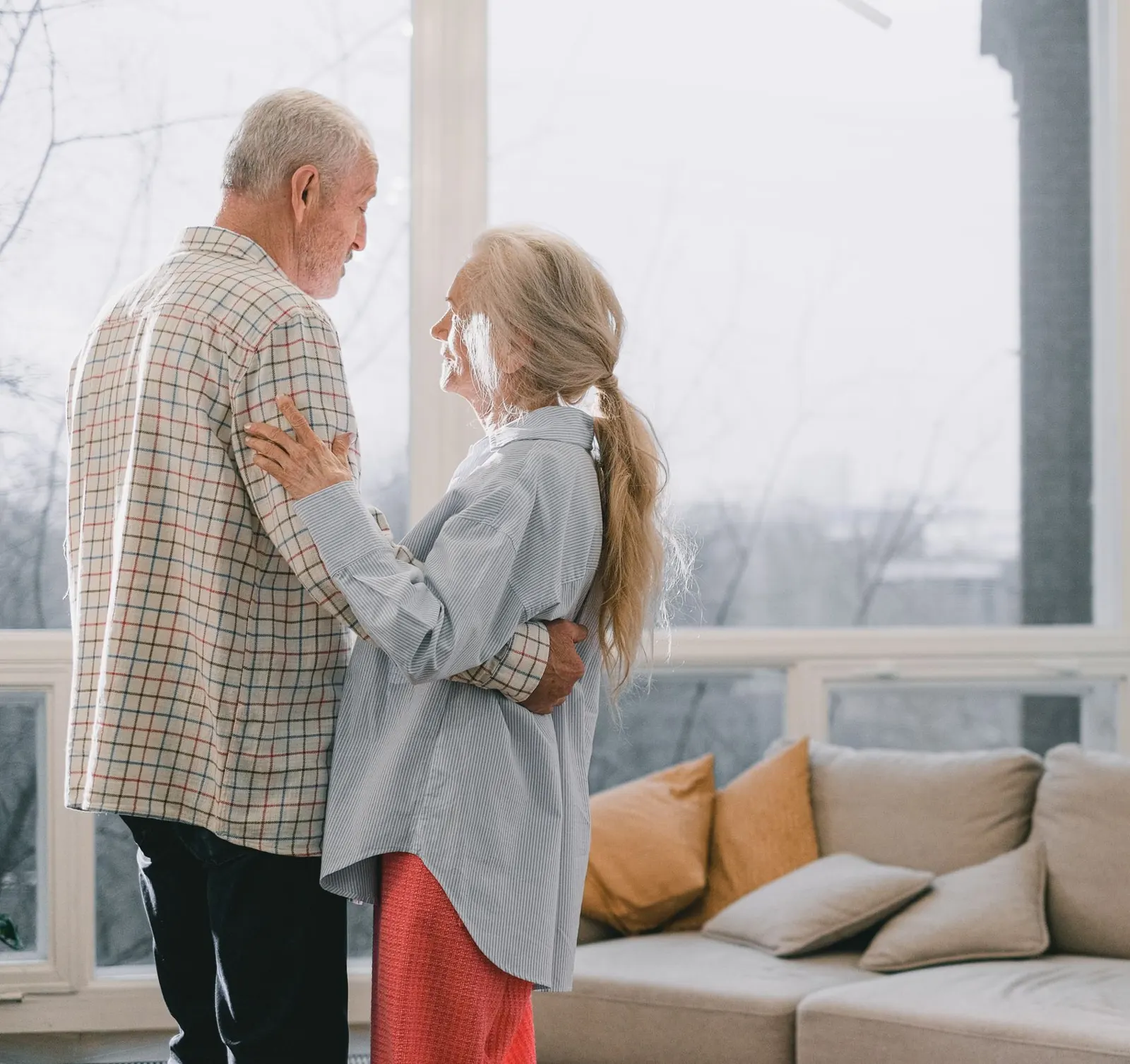 An older couple sharing a slow dance in the bright living room of their home