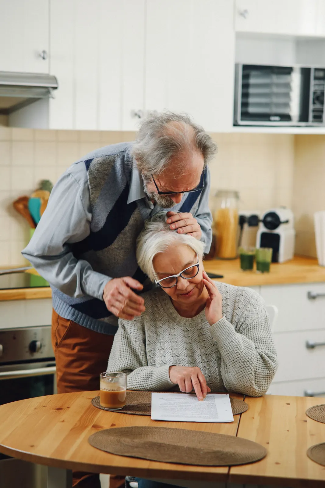Older couple reading through papers together at a bright kitchen table