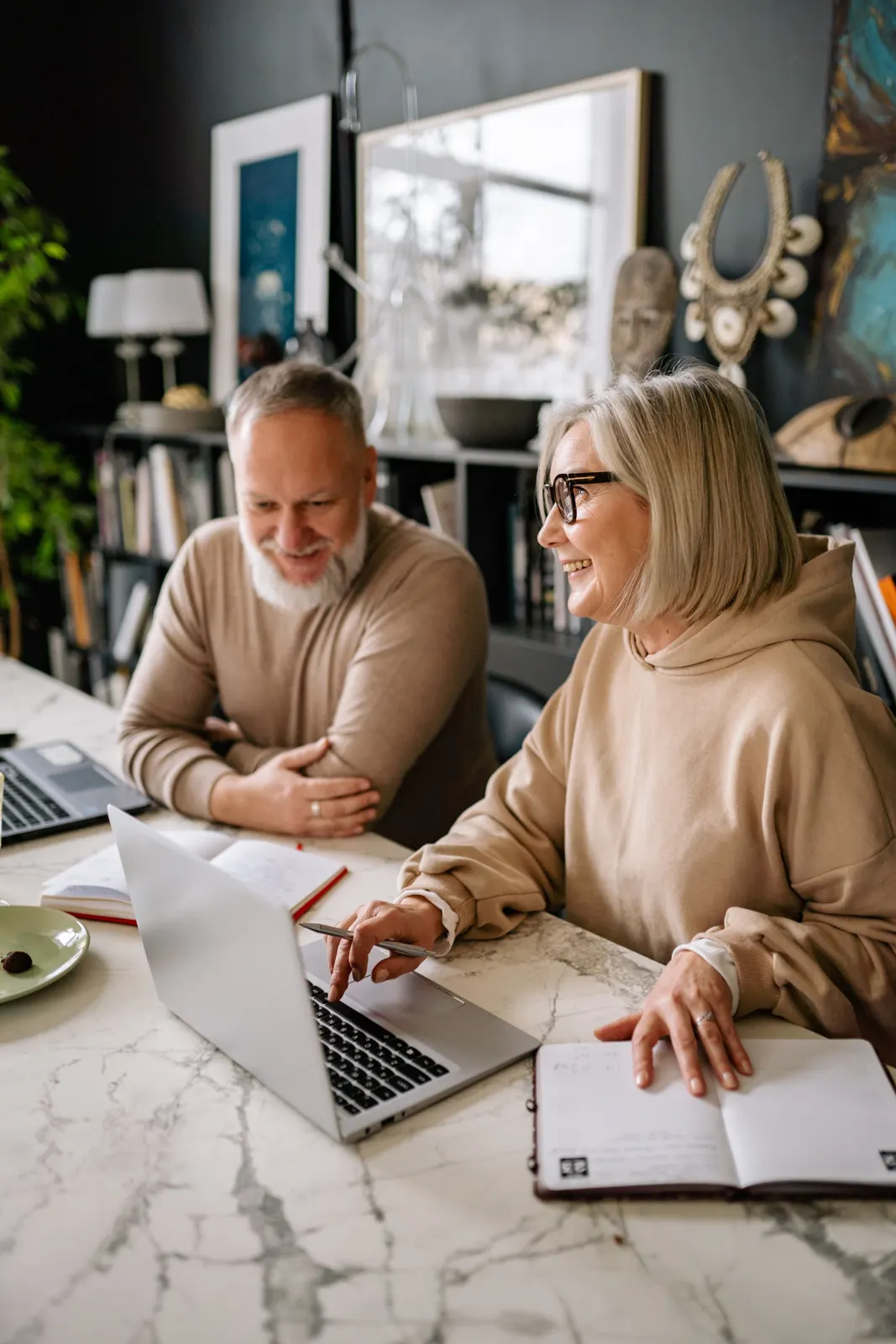 Older couple planning together at a table with a laptop and notebook