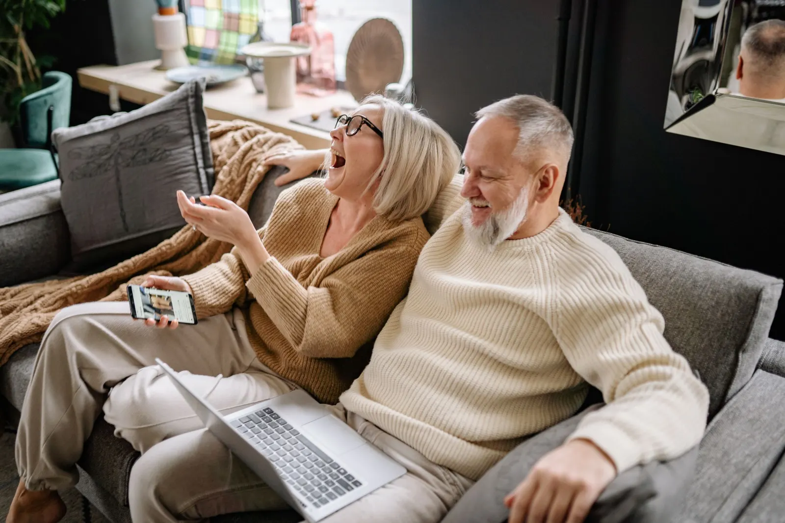 Older couple laughing together on the sofa